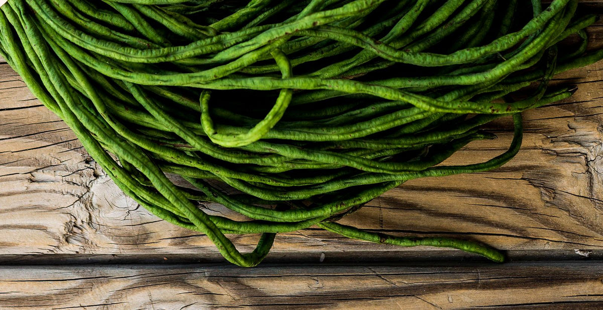 Seikat kacang panjang hijau tua di atas meja kayu